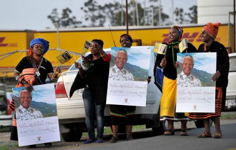 Community members singing next to the area where the procession will stop for a few seconds before reaching the Mandela home. Source: GCIS