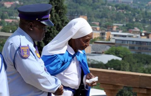 A nun is escorted by a SAPS official after seeing Mandela's remains at the Union Buildings. Source: GCIS