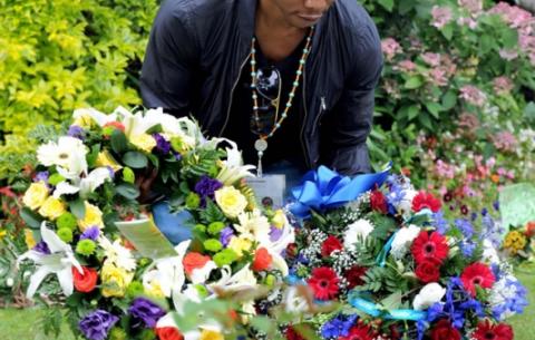Madiba's grandson Mbuso collecting tribute flowers from the public. Source: GCIS